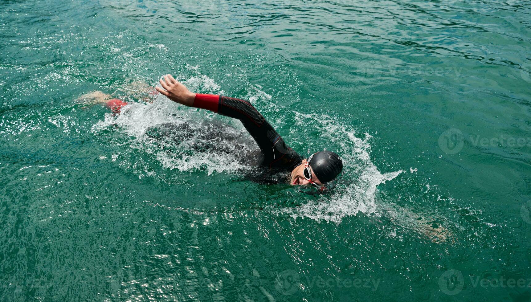 atleta di triathlon che nuota sul lago indossando la muta foto