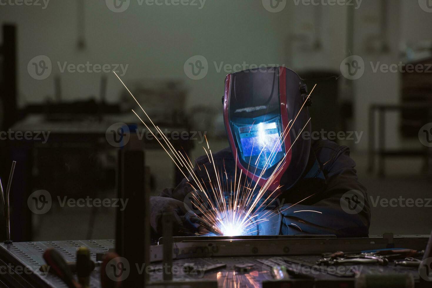 saldatore professionista dell'industria pesante che lavora all'interno della fabbrica, indossa il casco e inizia a saldare. messa a fuoco selettiva foto