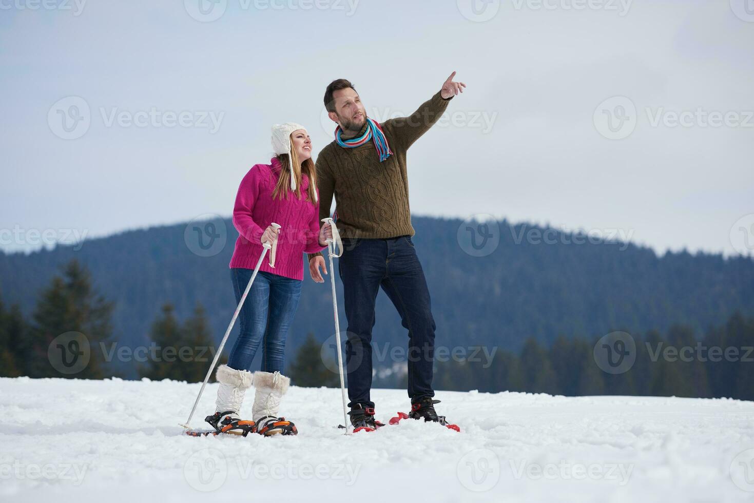 coppia divertendosi e camminando con le racchette da neve foto