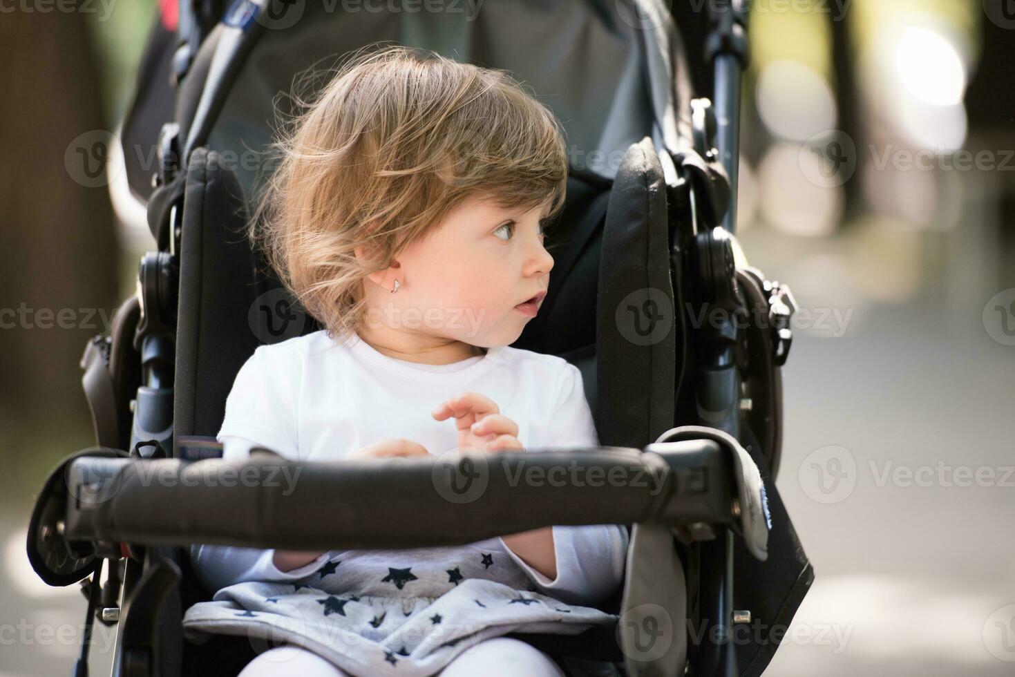 bambino ragazza seduta nel il carrozzina foto