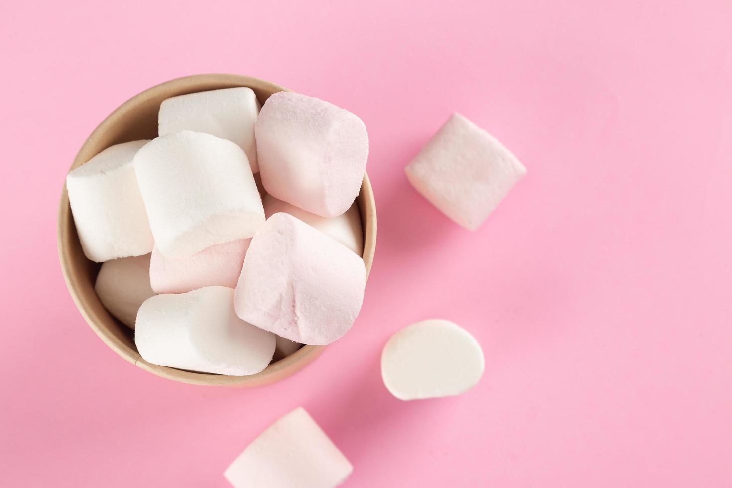 marshmallow nel secchio su sfondo rosa pastello foto