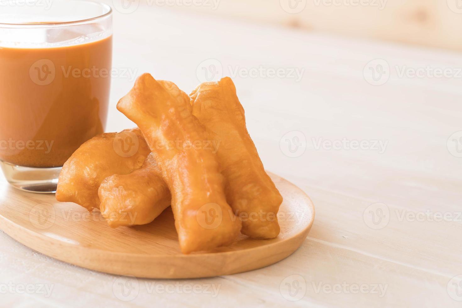 stecco di pasta fritto con tè al latte su legno foto