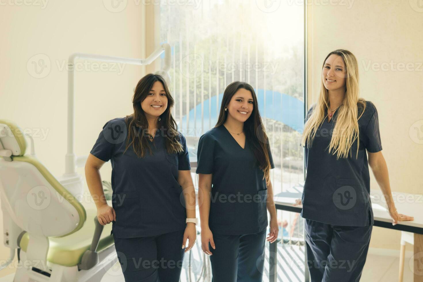 tre bellissimo femmina dentisti Sorridi e Guarda a telecamera nel dentale clinica. foto