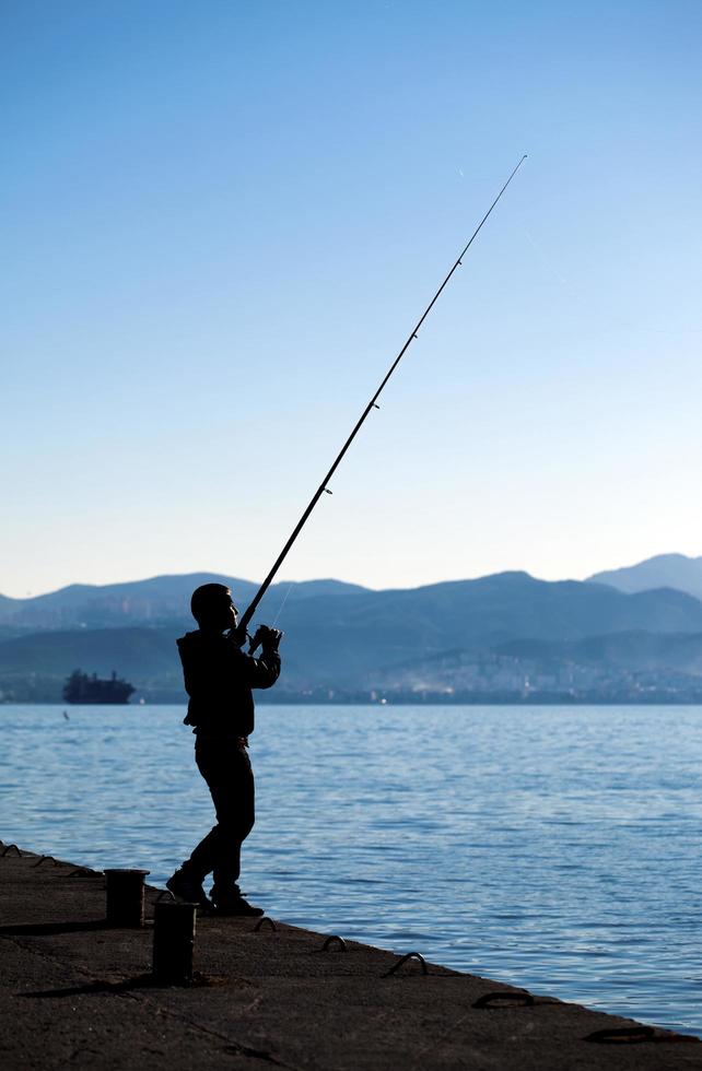 un ragazzo ombra vicino al mare che pesca foto