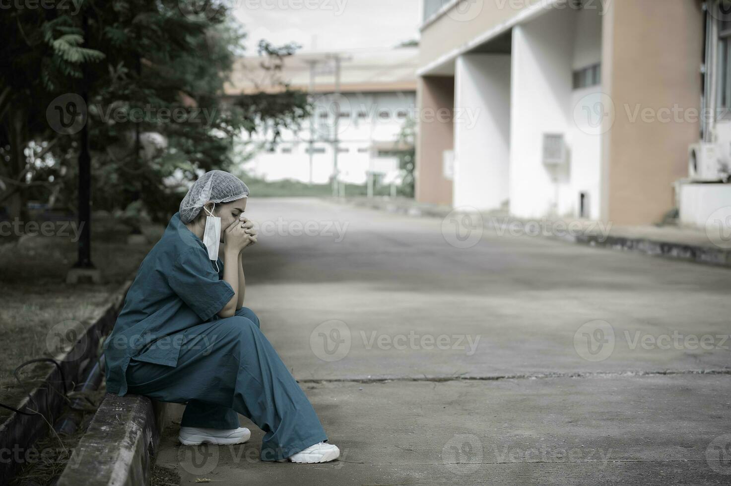 stanco depresso donna asiatica scrub infermiera indossa maschera facciale uniforme blu siede sul pavimento dell'ospedale, giovane donna medico stressato dal duro lavoro foto