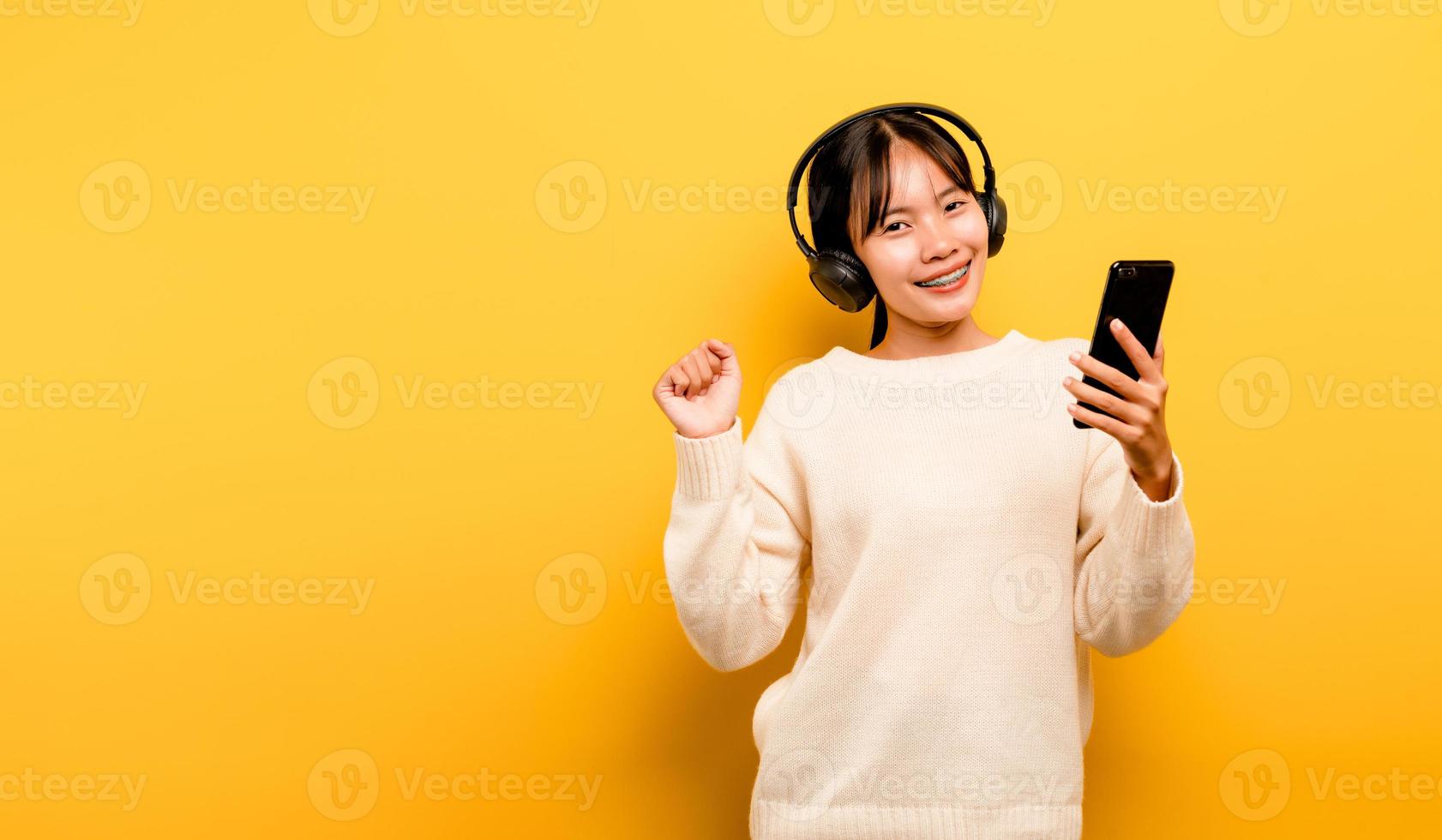 donna asiatica che usa felicemente il telefono e ascolta musica foto