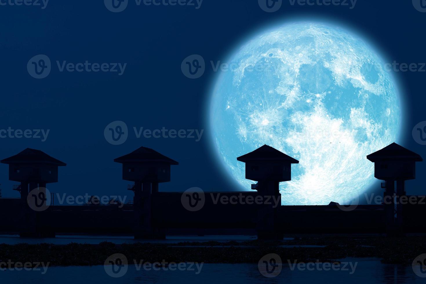 riflesso luna piena blu e diga silhouette nel cielo notturno scuro foto