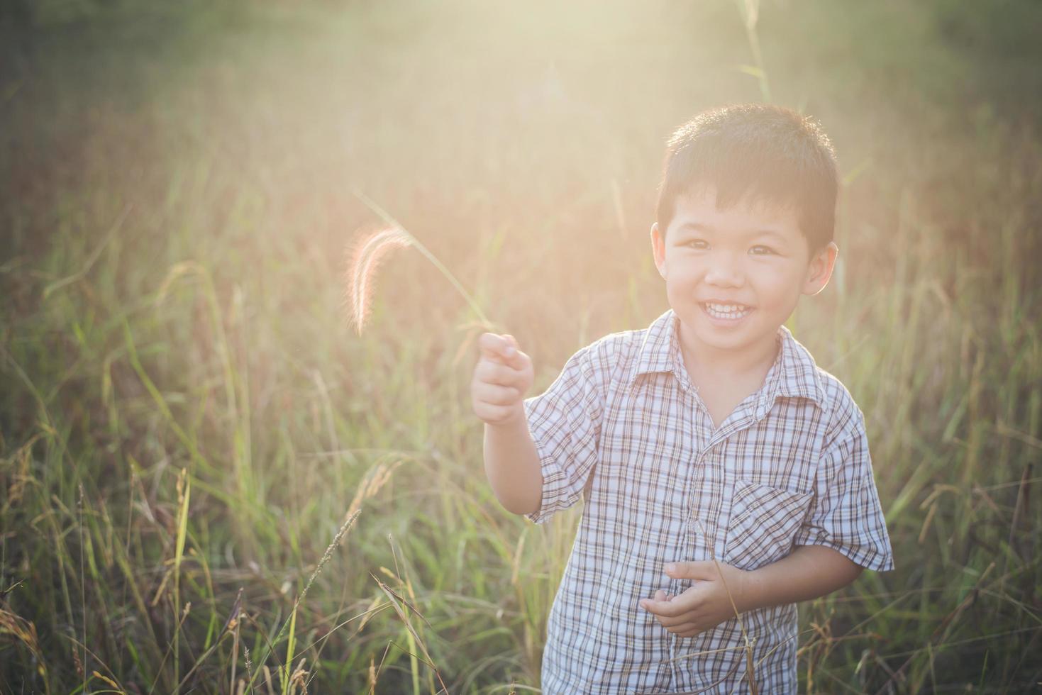 felice piccolo ragazzo asiatico che gioca all'aperto. carino asiatico. ragazzo in campo. foto