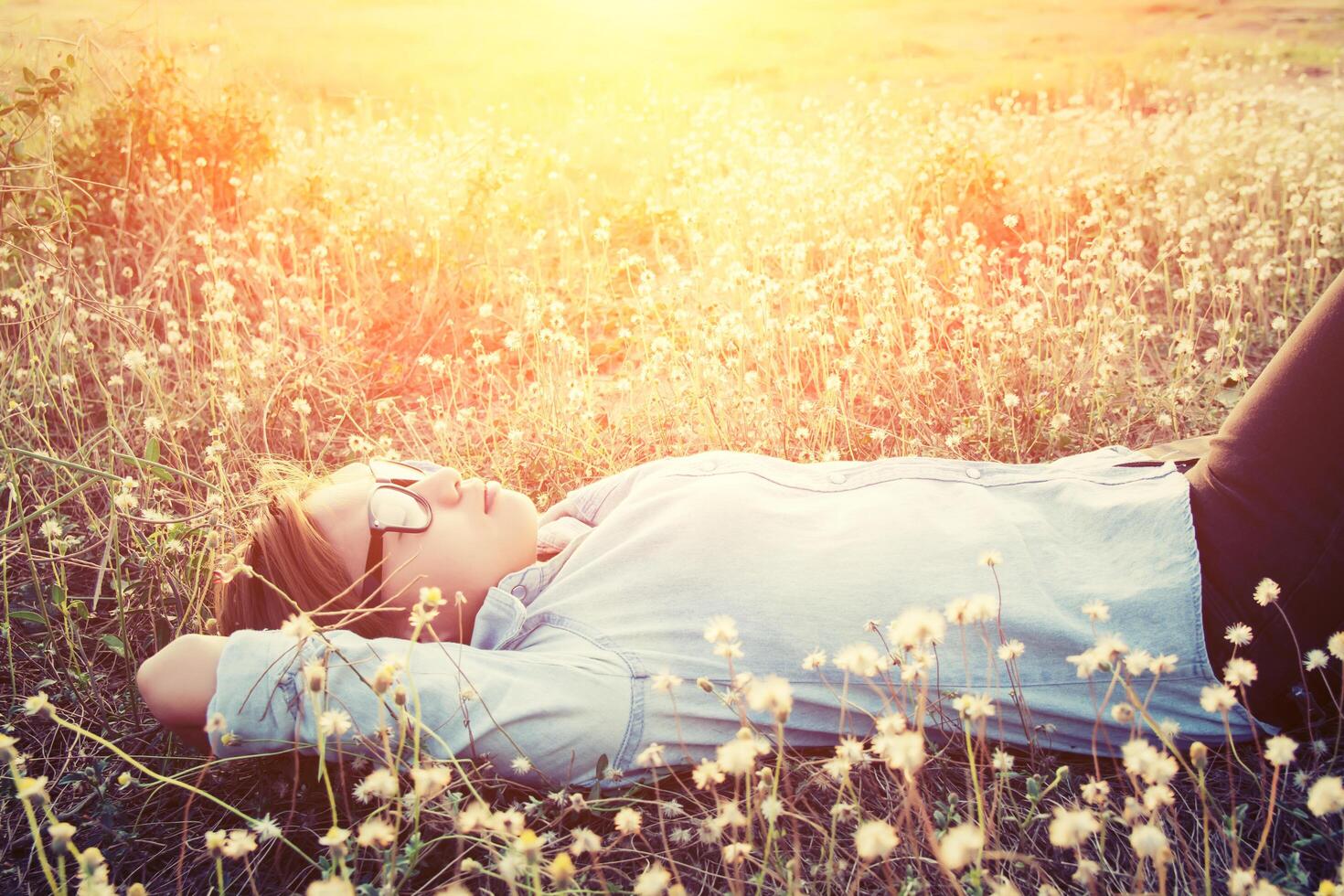 donna sdraiata sul campo di tarassaco chiudi gli occhi sentendosi a proprio agio foto