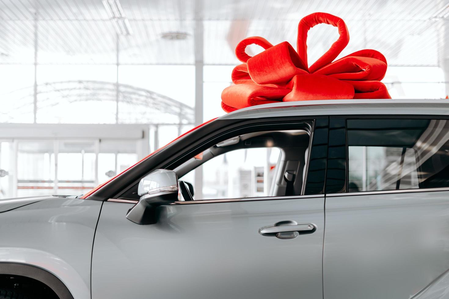 la nuova auto è avvolta in un fiocco rosso. bellissimo concetto di regalo foto