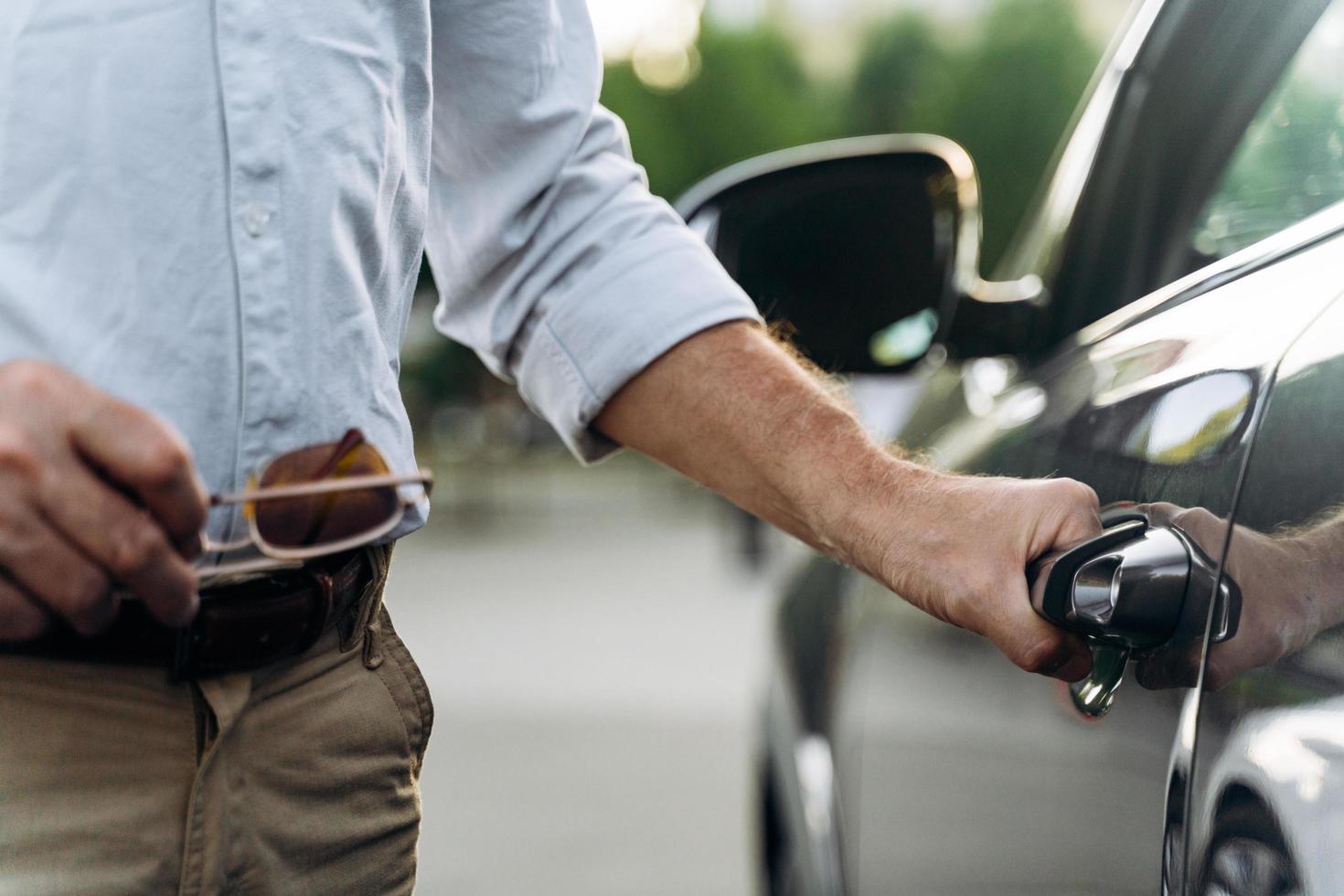 l'uomo anziano apre la portiera della sua auto con accesso senza chiave. foto