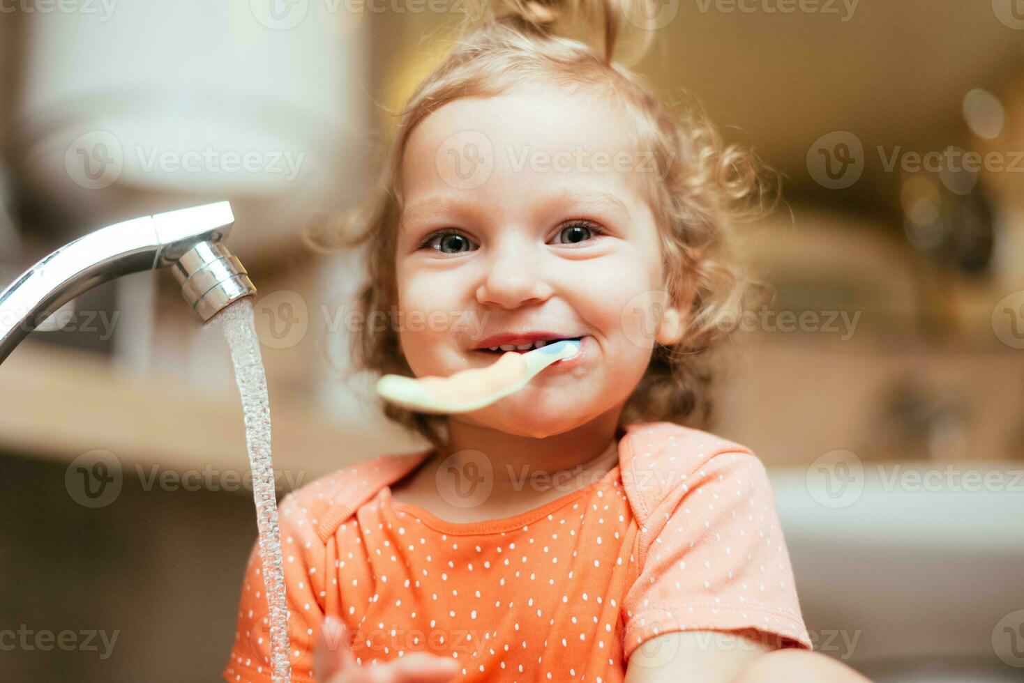 contento ridendo bambino ragazza spazzolatura sua denti nel il bagno foto