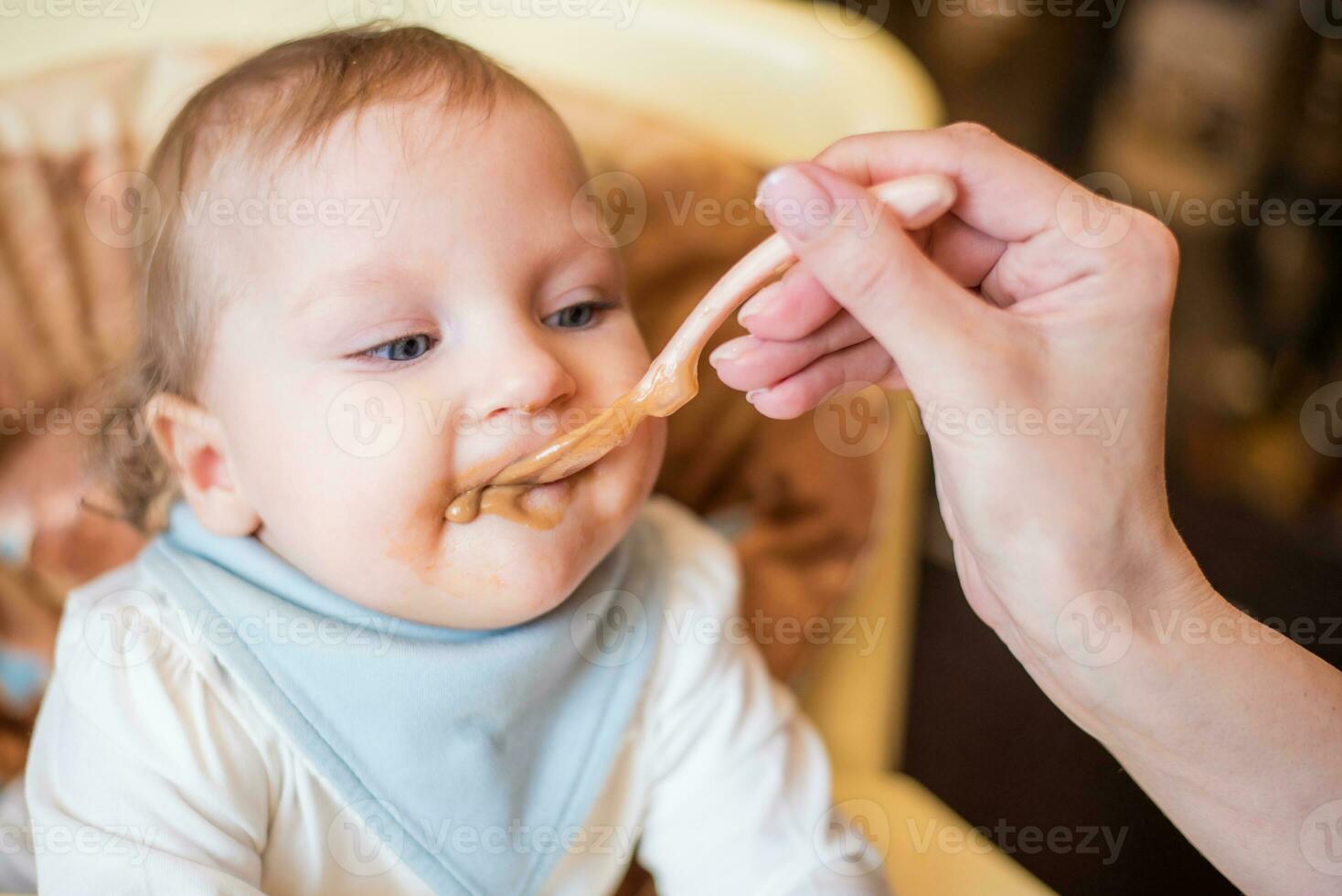 mamma feed un' contento bambino frutta puré a partire dal un' cucchiaio. primo cibo foto