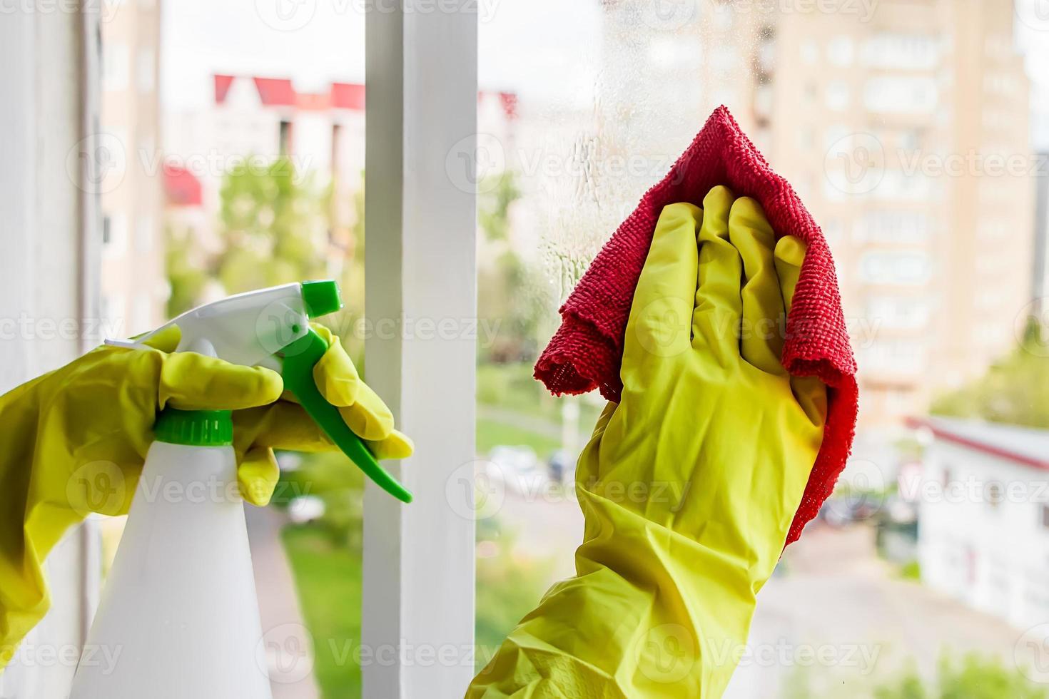 donna in guanti di gomma gialli pulisce il vetro foto