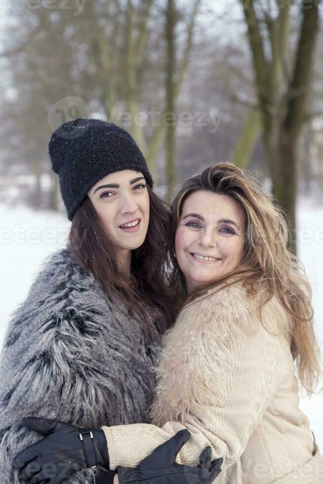 mamma e figlia abbracciare ogni con amore nel il neve foto