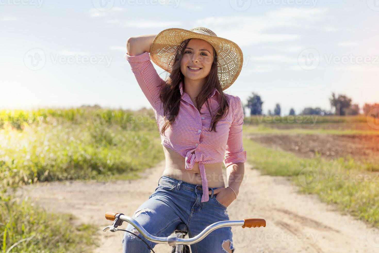 bella giovane donna su bicicletta nel un' nazione strada foto