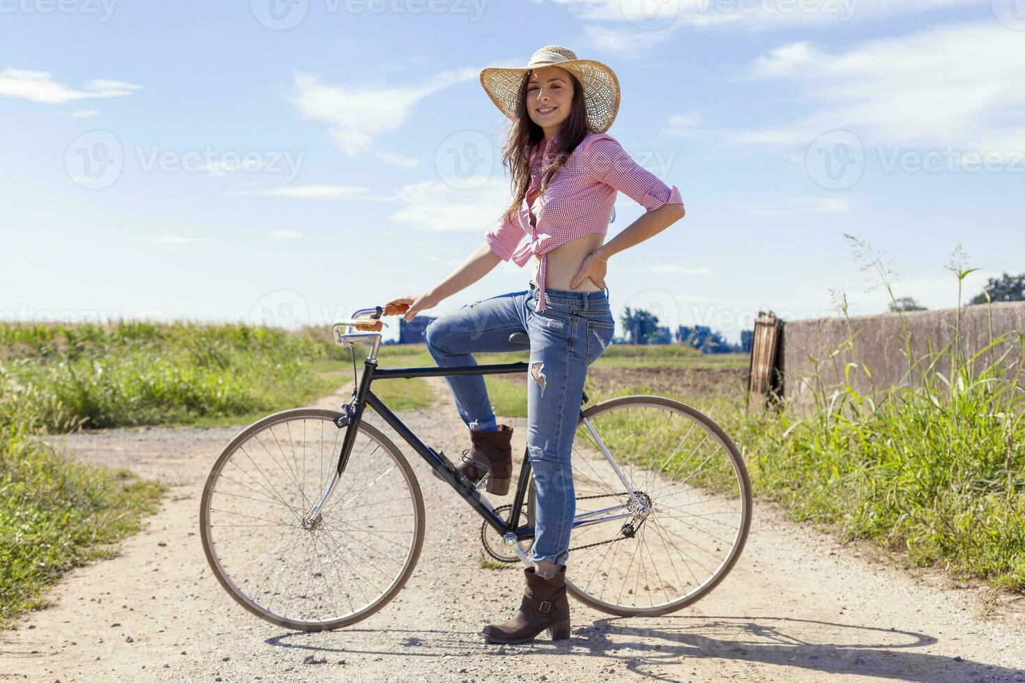 bella giovane donna su bicicletta nel un' nazione strada foto