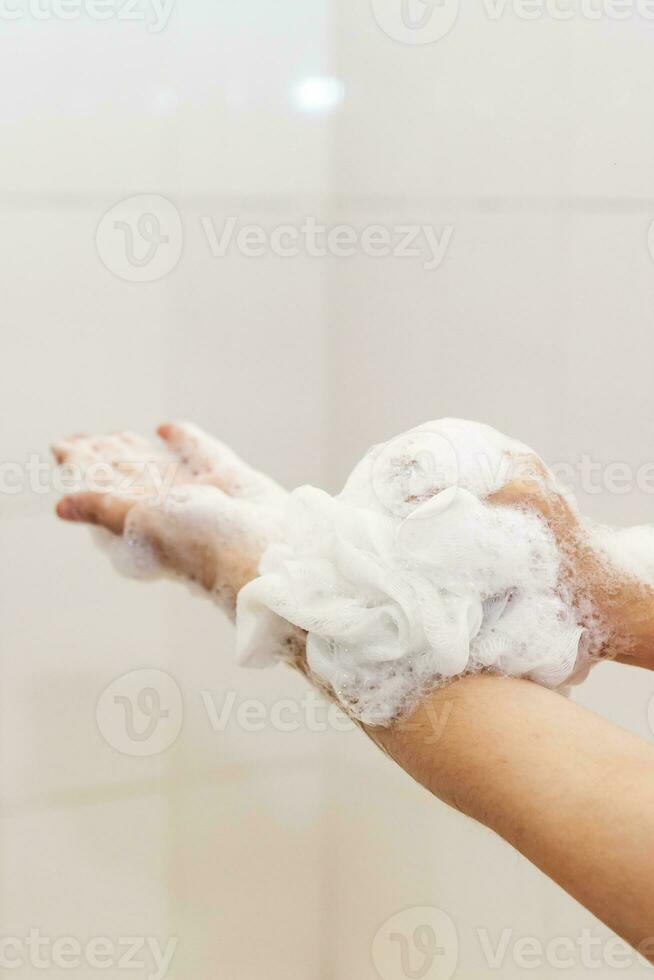 donna lavaggio mani con un' spugna nel il bagno. femmina lavaggio braccia con un' schiumoso spugna nel il bagno. corpo cura e pulito concetto foto