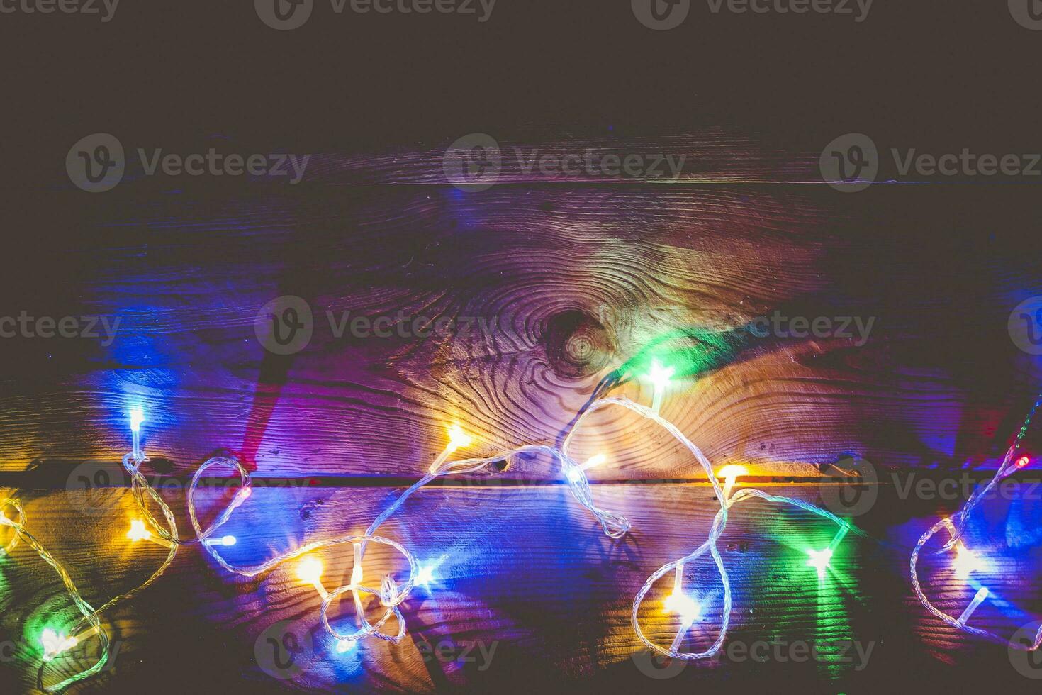 Natale decorativo luci. Natale ghirlanda luci su Di legno. colorato natale leggero bulbi su rustico Marrone tavola foto