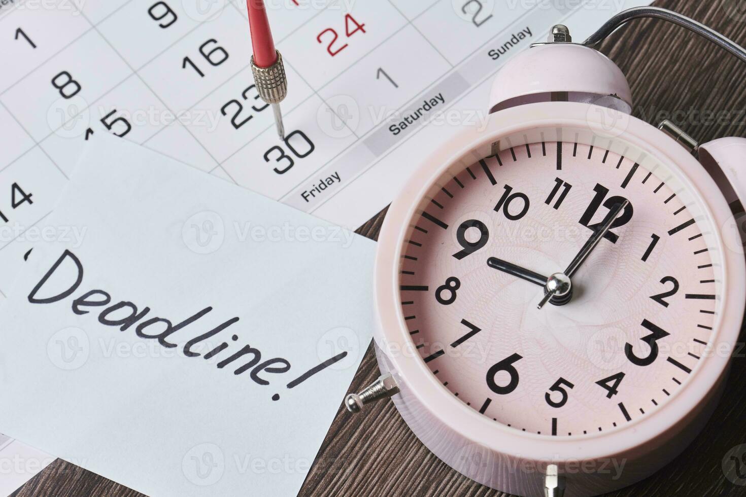 Scadenza testo su pezzo di carta, allarme orologio e mensile calendario foto