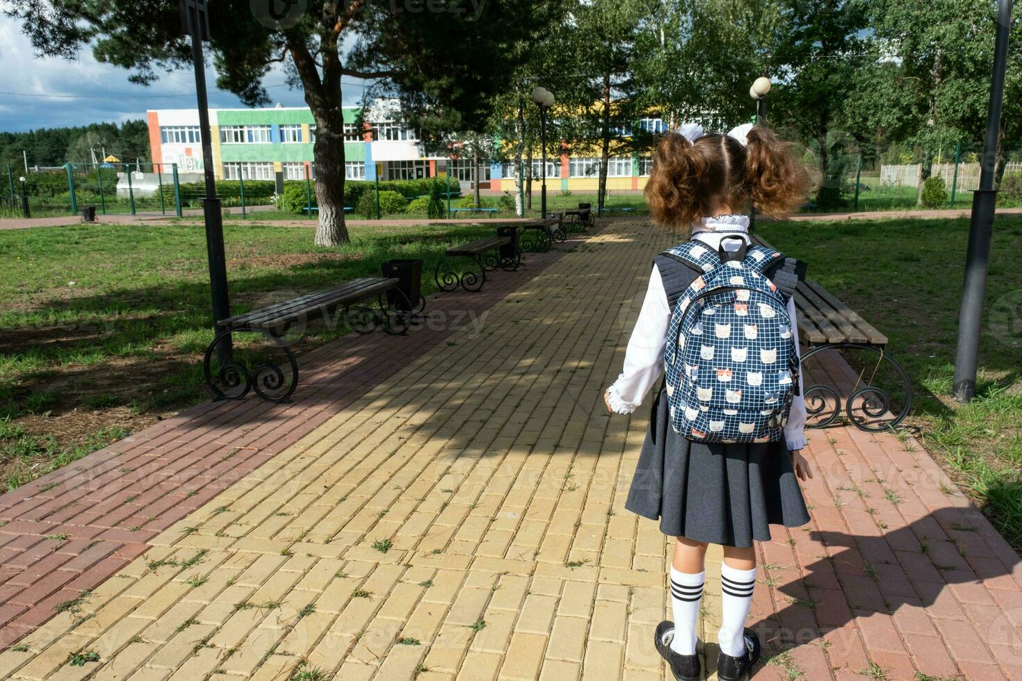 allievo con zaino e nel un' scuola uniforme nel scuola cortile indietro per il telaio. indietro per scuola, settembre 1. un' contento alunno. primario formazione scolastica, elementare classe. strada per vita, per conoscenza foto