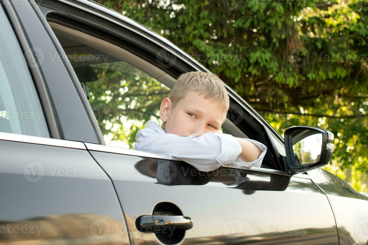 il triste ragazzo avuto su di il auto finestra e sembra lontano. Aperto auto finestra foto