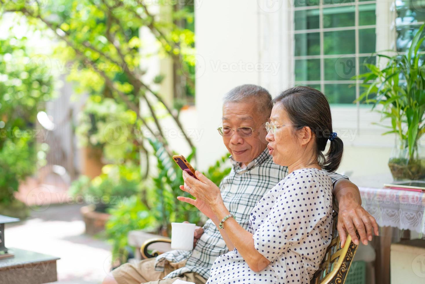 coppia asiatica anziana che utilizza smartphone insieme a casa foto