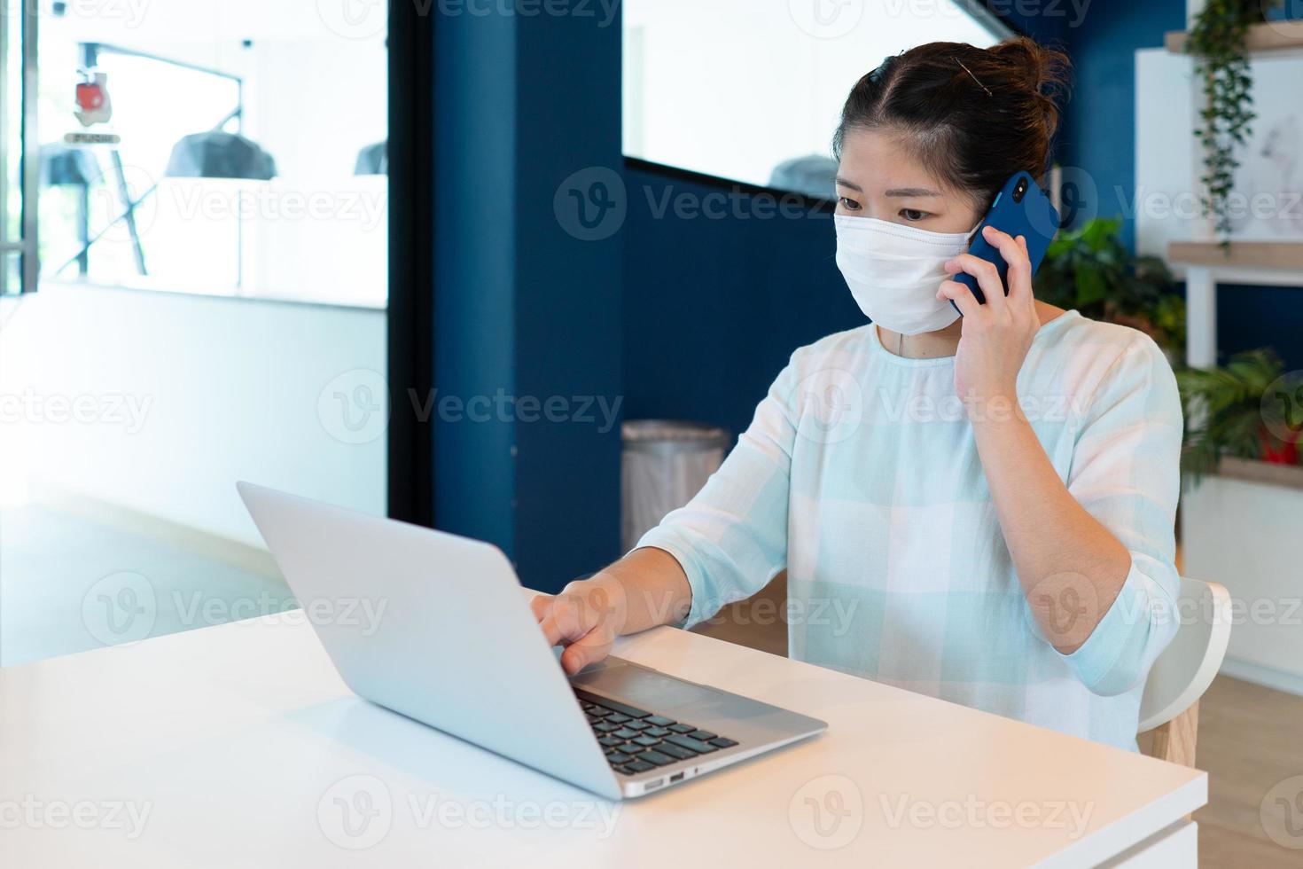 la donna indossa la maschera e usa il computer per videochiamare nello spazio di lavoro. foto