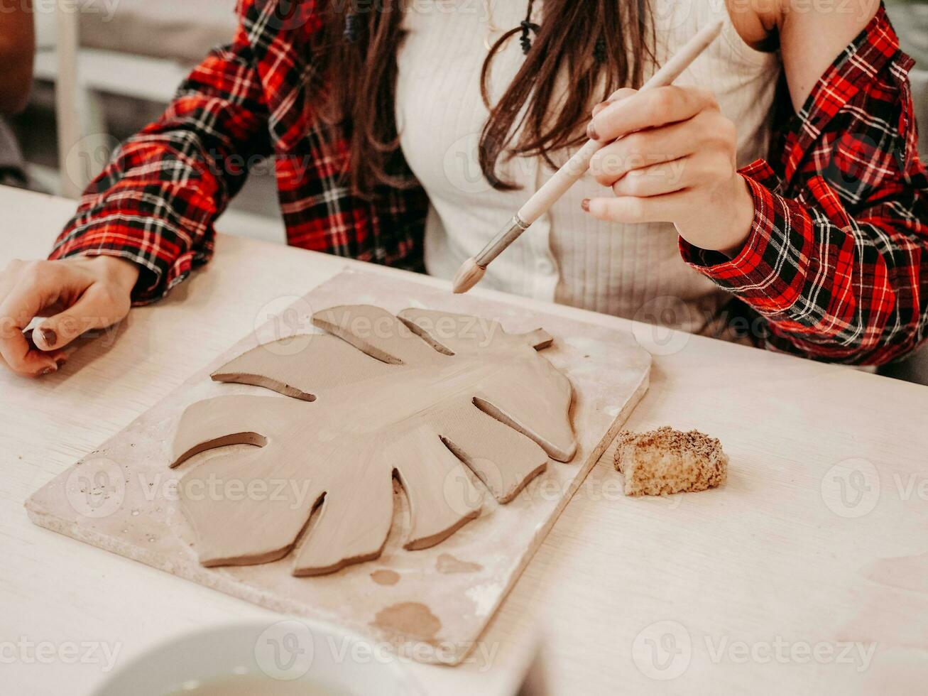 argilla mestiere. fatto a mano. argilla piatto nel il forma di un' mostro. ragazza Lavorando con un' spazzola nel il laboratorio foto