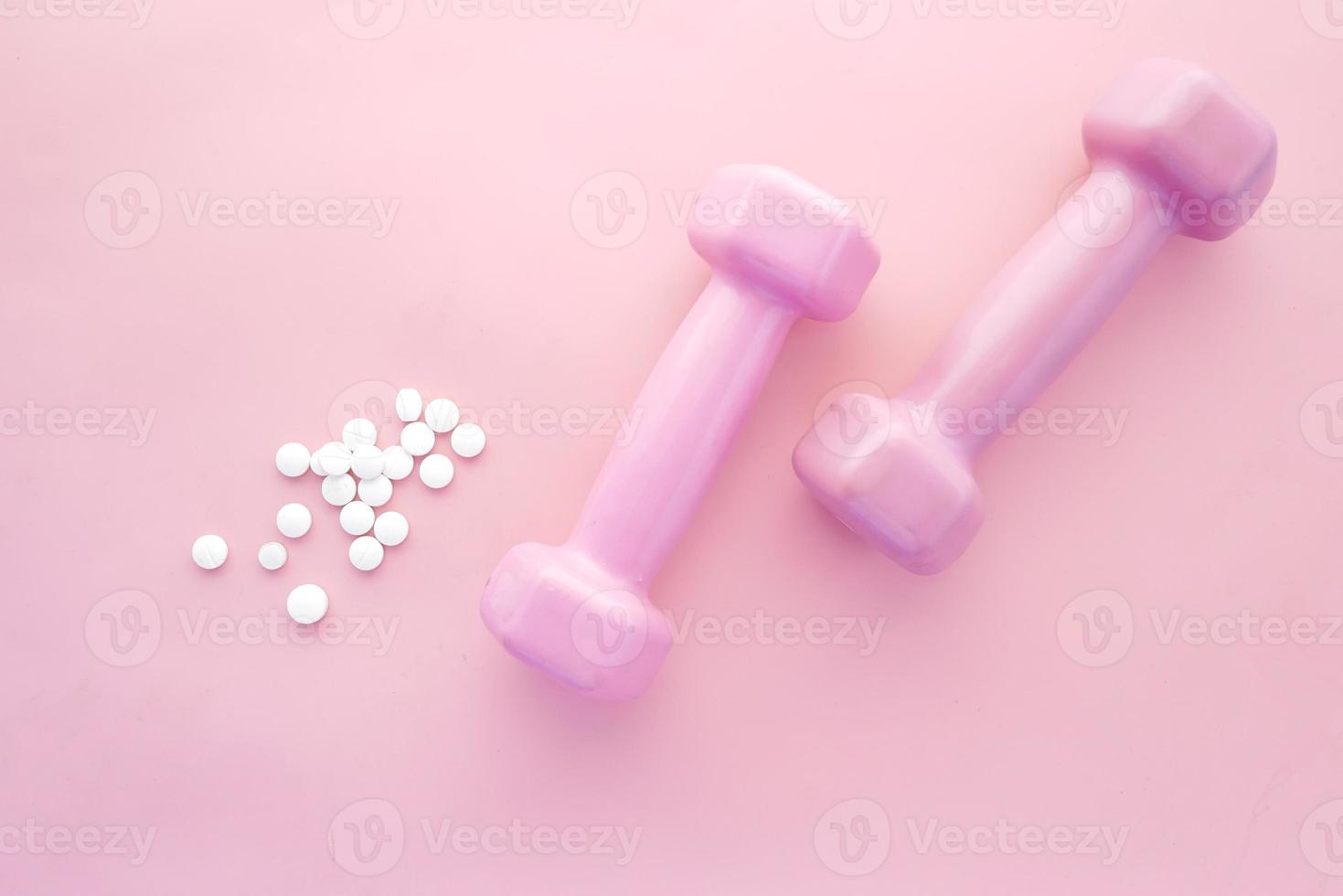 manubrio di colore rosa e pillole mediche su rosa foto