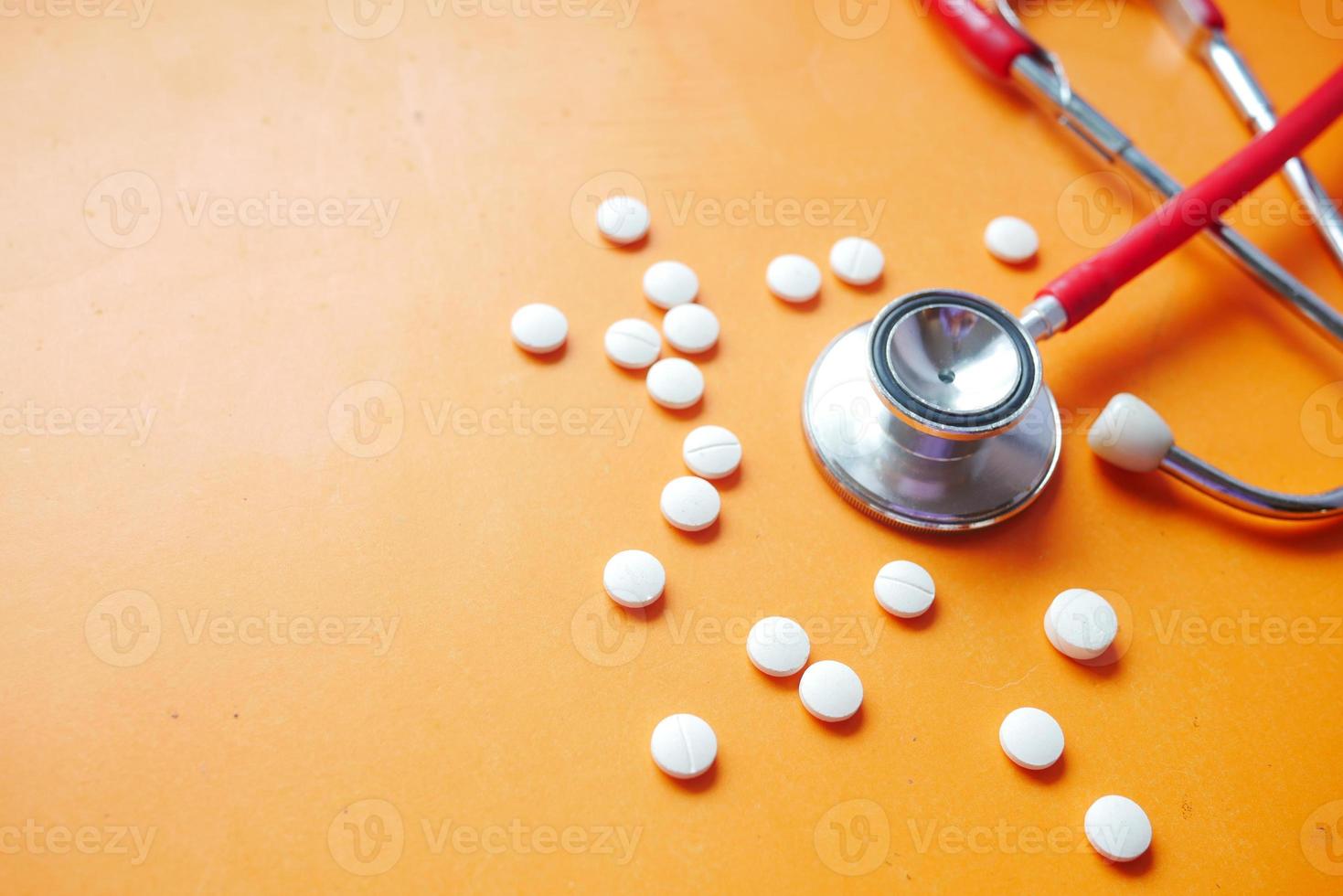 stetoscopio e pillole mediche su sfondo arancione foto