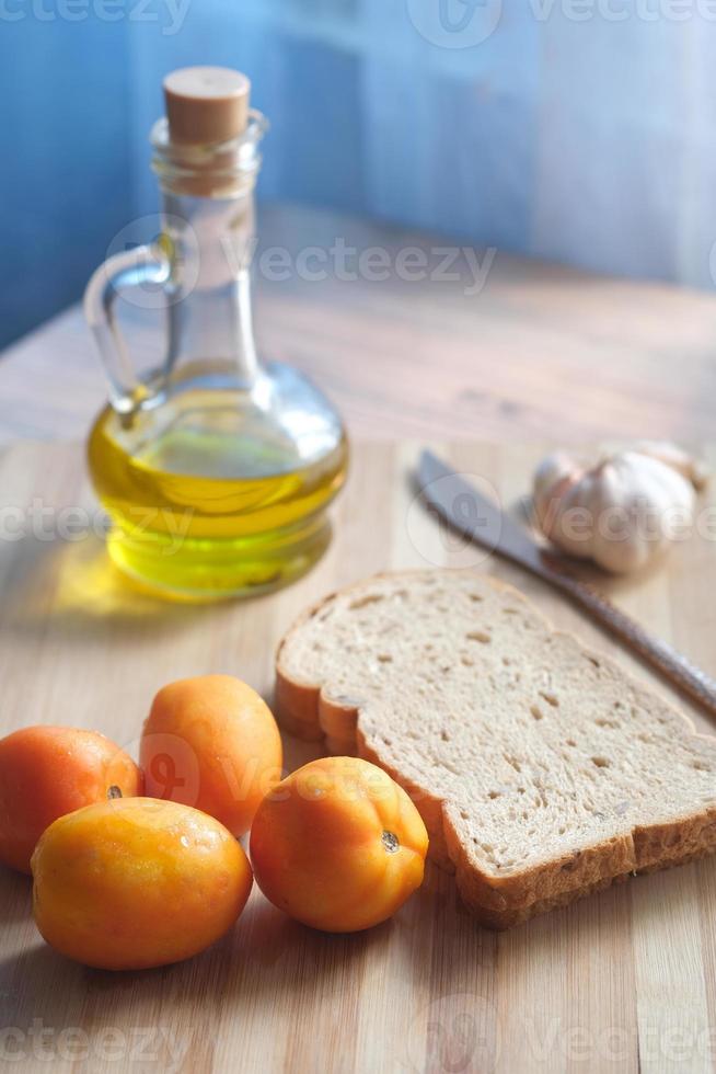 primo piano di aglio, pomodoro e olio d'oliva sul tavolo foto