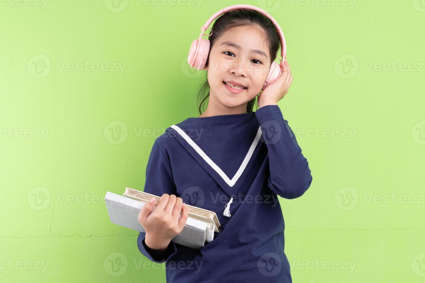 ritratto di bambino asiatico che tiene libro su sfondo verde foto