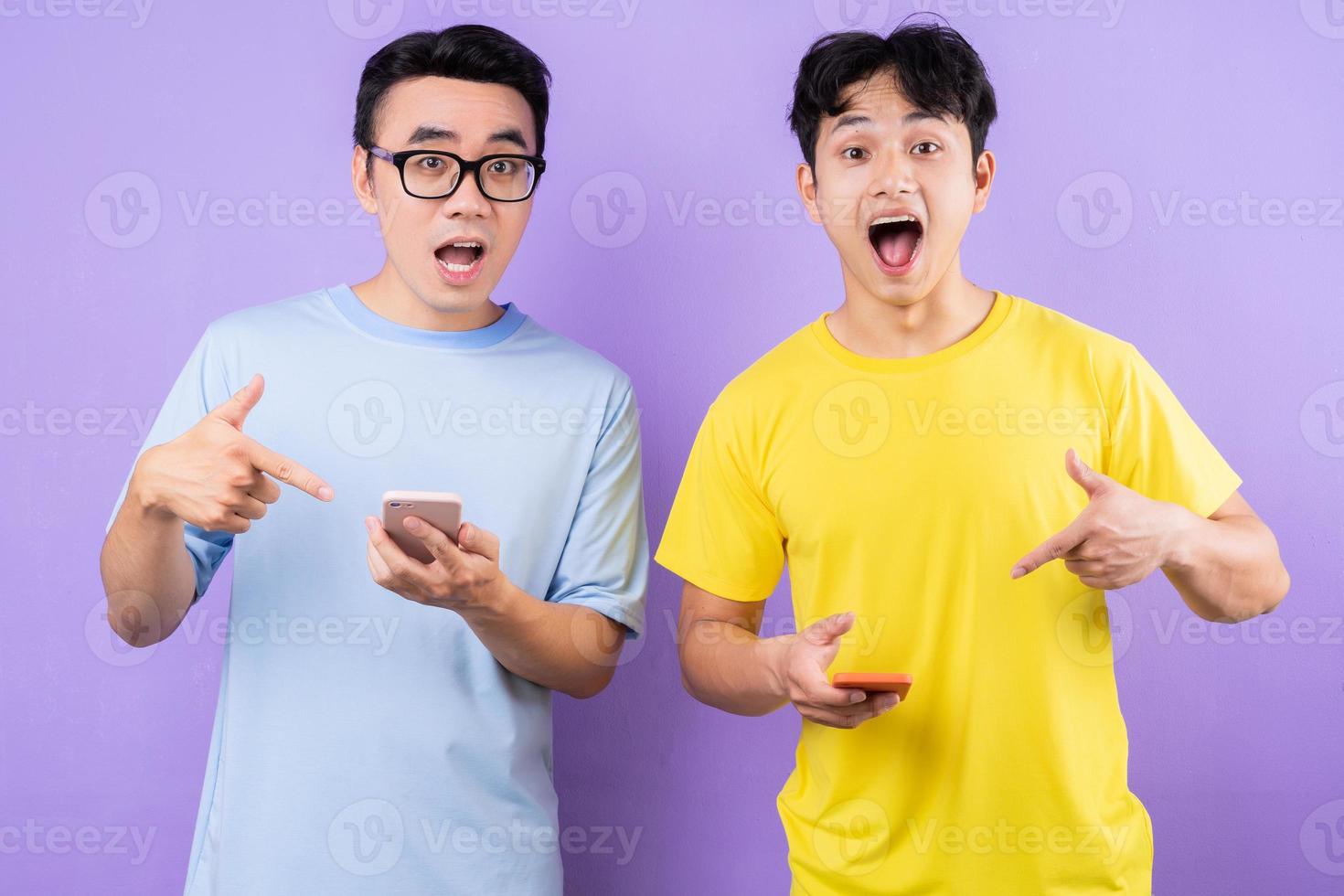 due fratelli asiatici che usano i telefoni cellulari su sfondo viola foto
