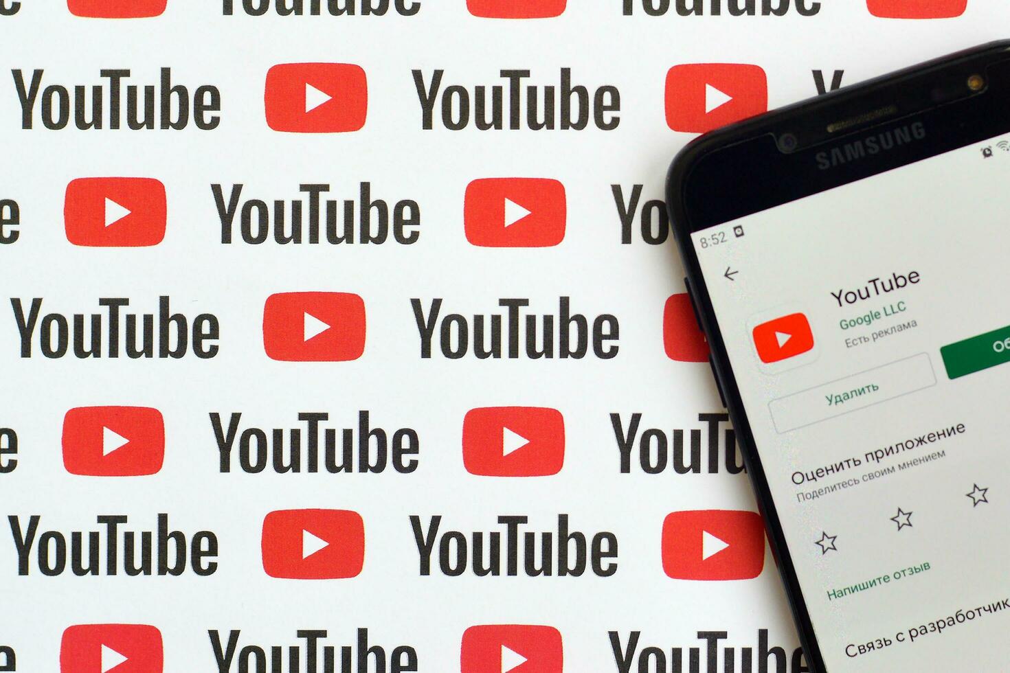 Youtube App su Samsung smartphone schermo su carta bandiera con piccolo Youtube loghi e iscrizioni. Youtube è Google filiale e americano maggior parte popolare condivisione video piattaforma foto