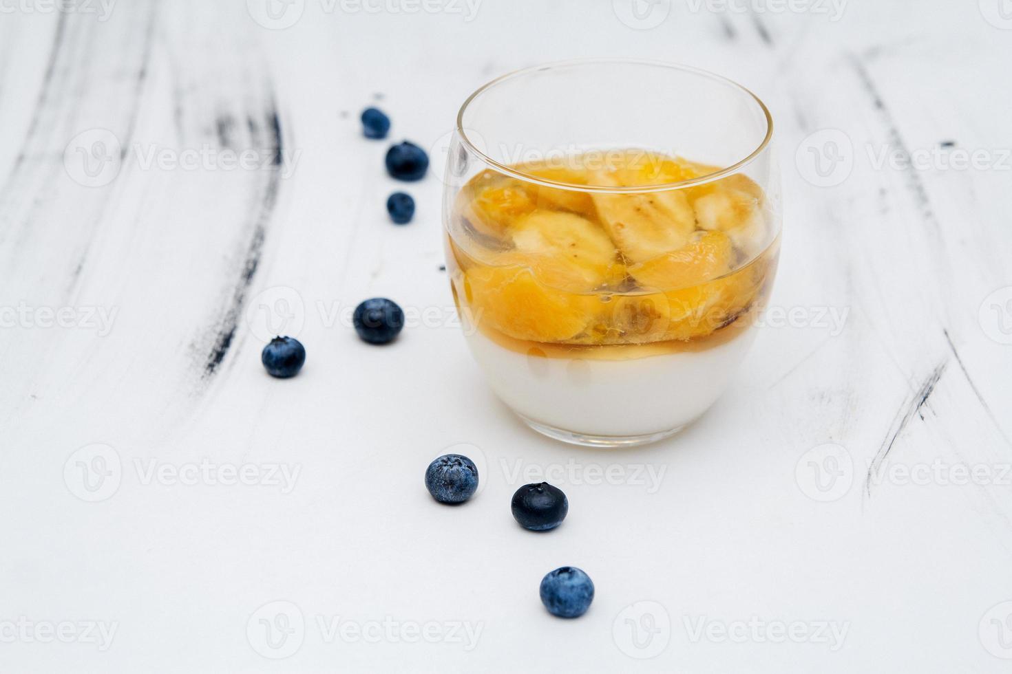 gelatina di frutta colorata in un bicchiere su sfondo bianco con mirtilli foto