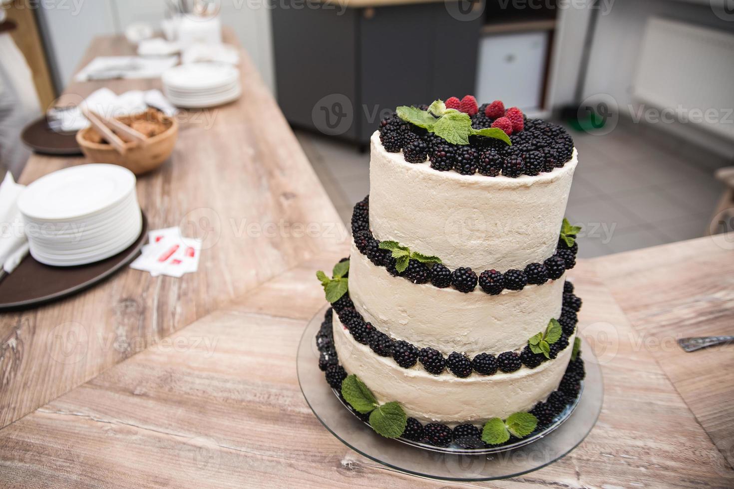 torta nuziale cremosa decorata con frutti di bosco sul tavolo foto