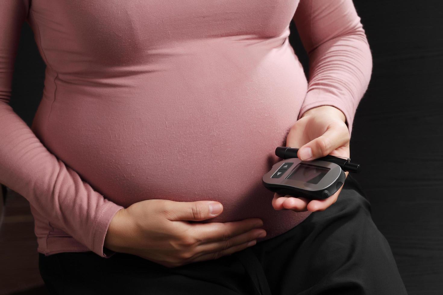 donna incinta che tiene il misuratore del livello di zucchero nel sangue, salute della gravidanza foto