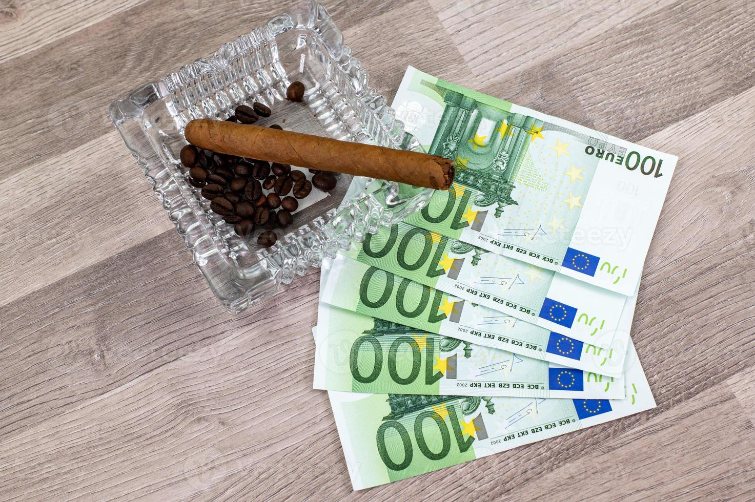 Banconote da 100 euro e posacenere con sigaro foto