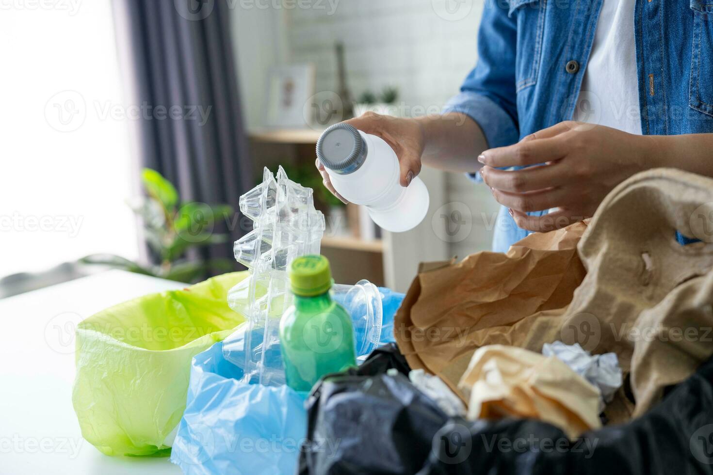 donna nel casuale Abiti mette vuoto plastica bottiglie in raccolta differenziata bidone a casa foto