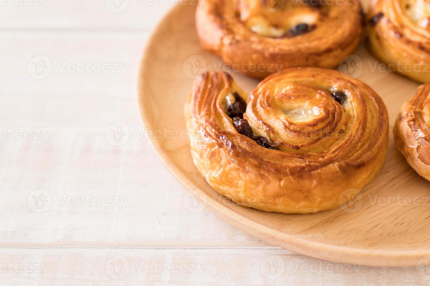 rotolo di uvetta alla cannella su piatto di legno foto