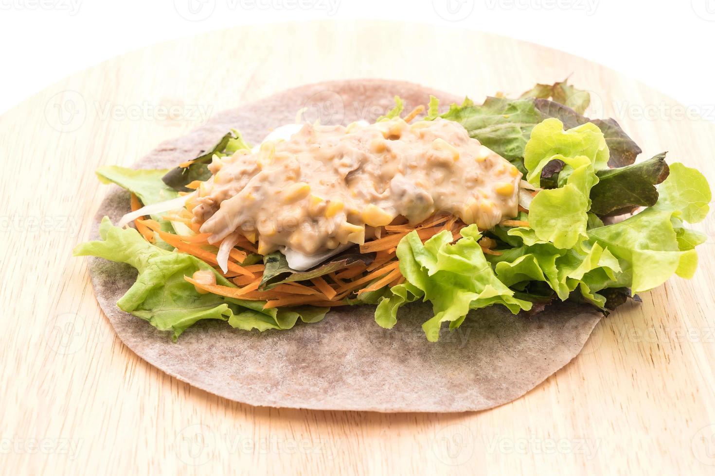 avvolgere il rotolo di insalata con tonno e insalata di mais su piatto di legno foto