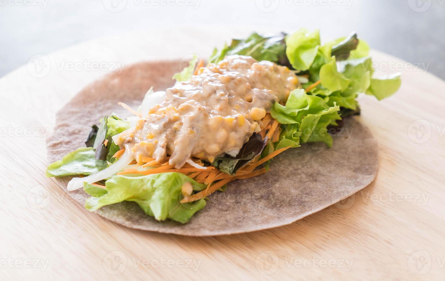 avvolgere il rotolo di insalata con tonno e insalata di mais su piatto di legno foto