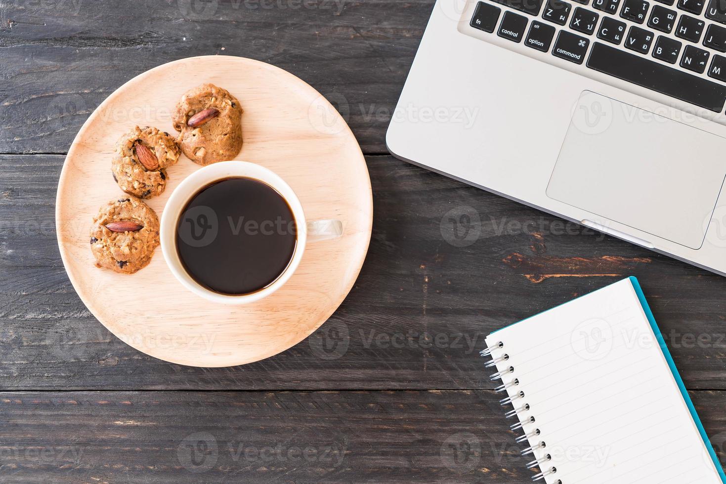 caffè nero e biscotti con laptop e notebook sul tavolo foto