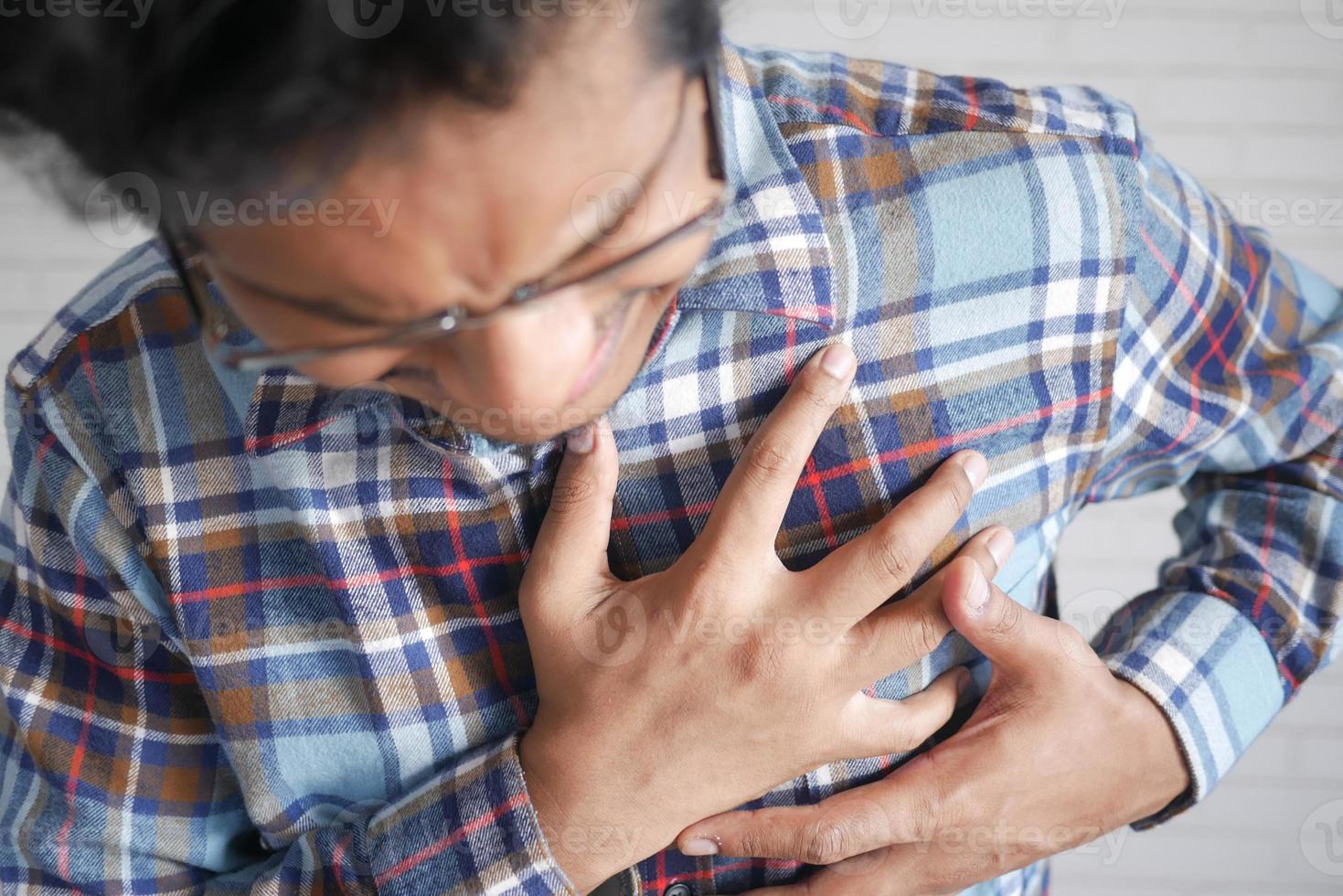 giovane che soffre di dolore al cuore e tenendo il petto con la mano foto