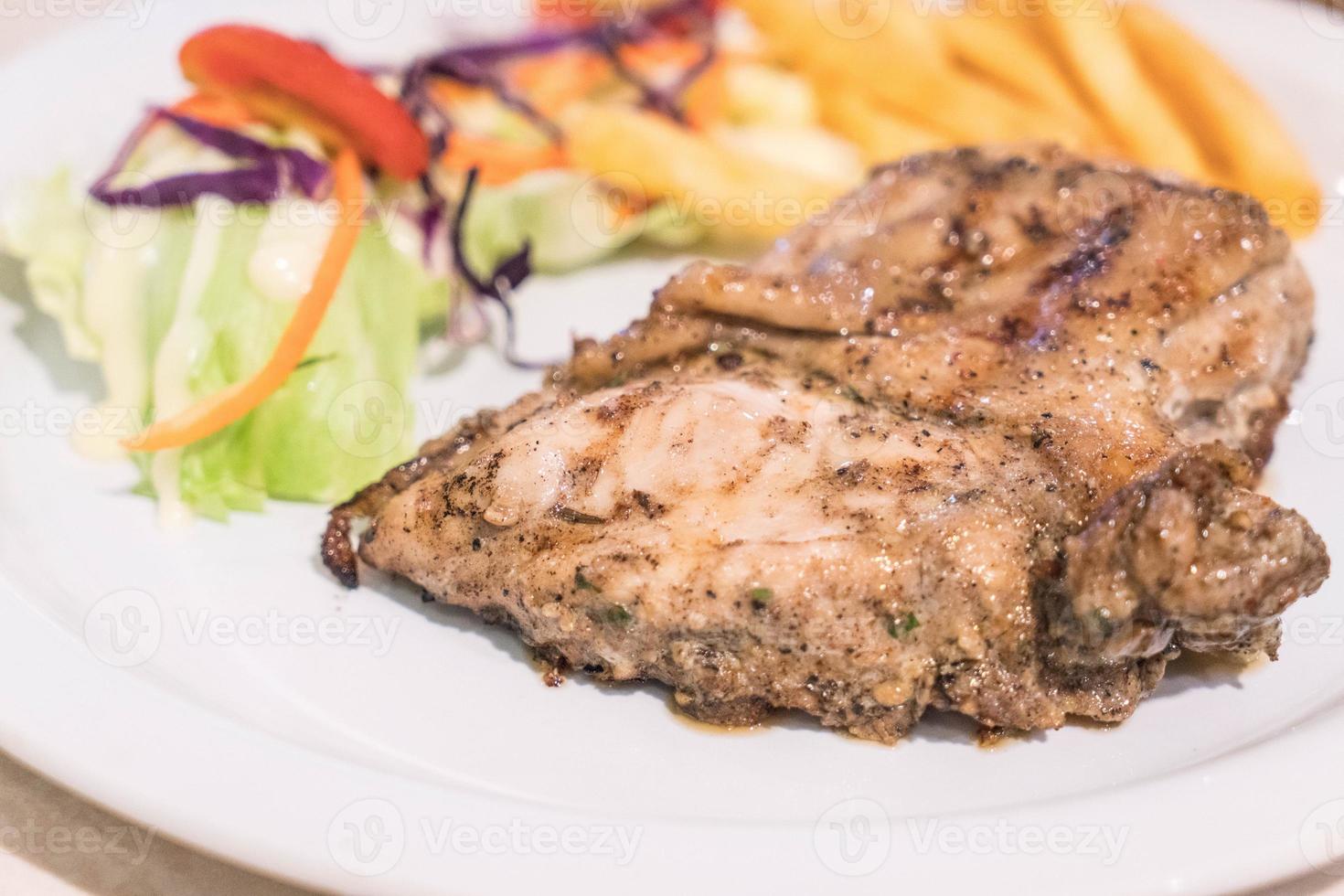 bistecca di pollo con peperoni neri su piatto bianco foto