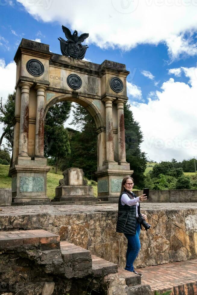 femmina turista assunzione immagini a il arco di trionfo nel boyaca costruito nel memoria di il 3 gare meticcio, creolo e spagnolo quale partecipato nel il processi di indipendenza di Colombia. foto