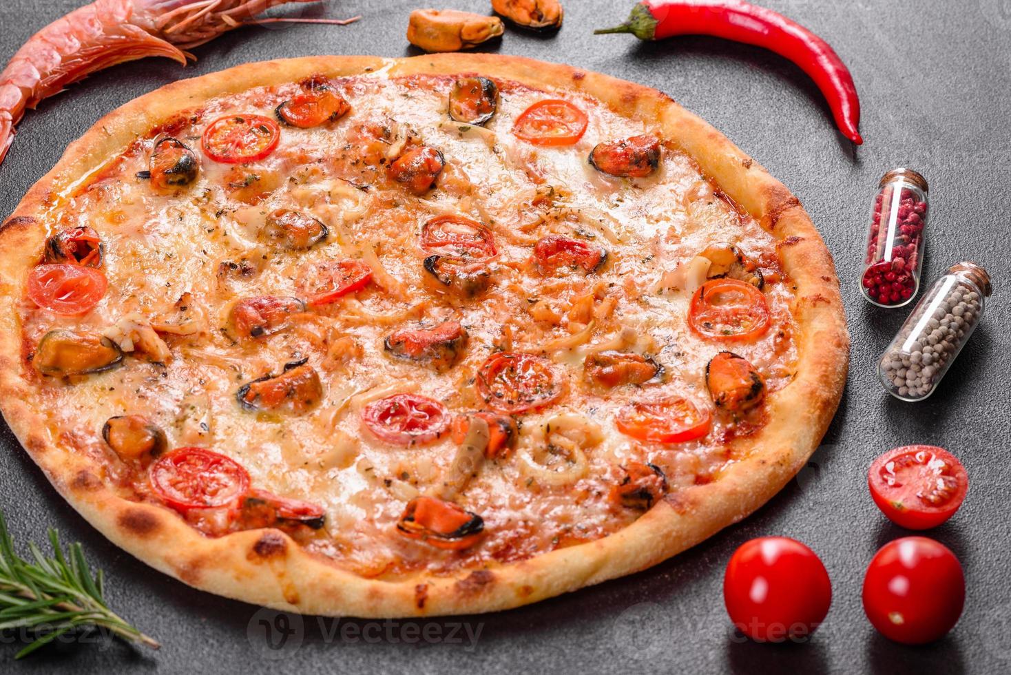 gustosa pizza a fette con frutti di mare e pomodoro su fondo di cemento foto