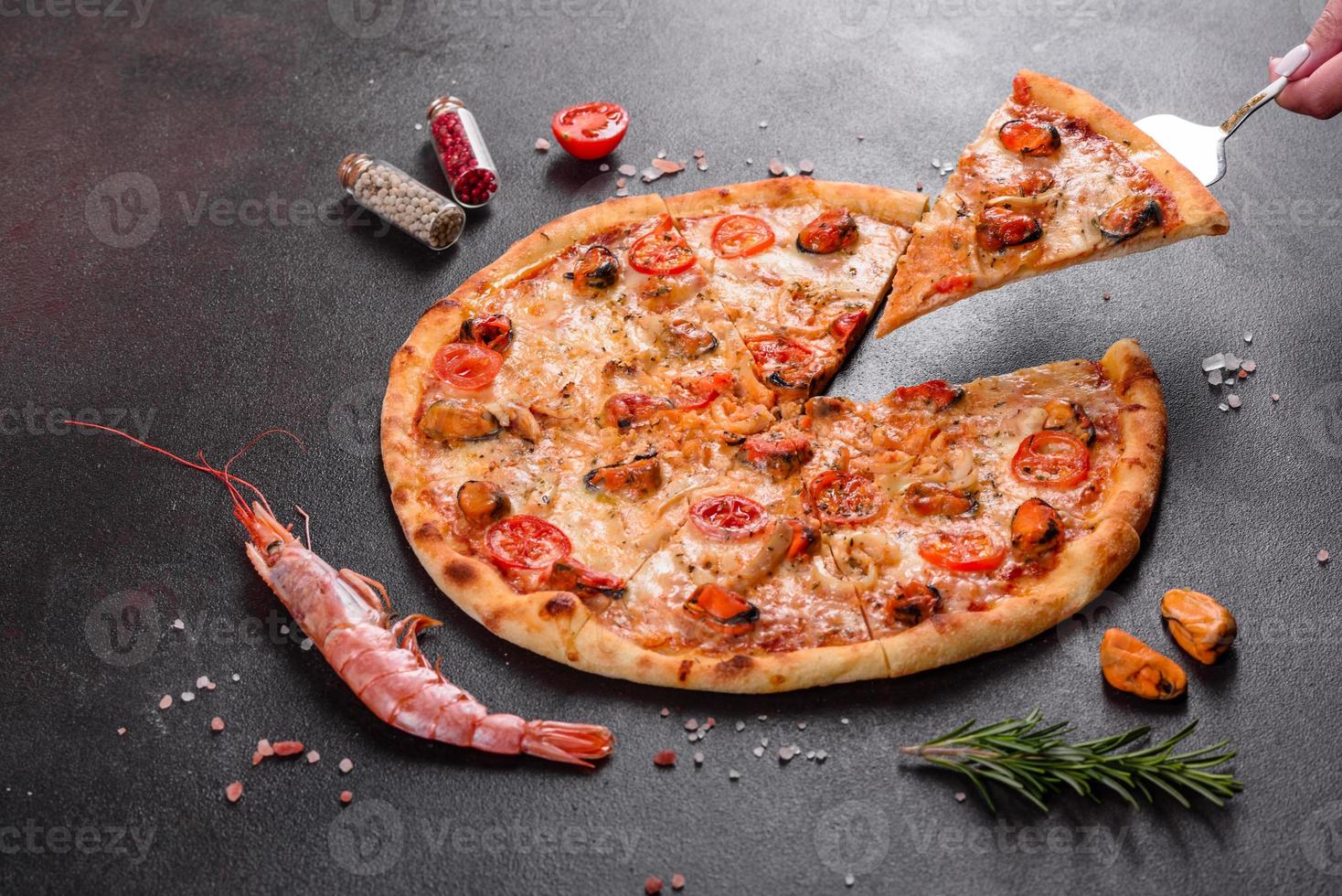 gustosa pizza a fette con frutti di mare e pomodoro su fondo di cemento foto