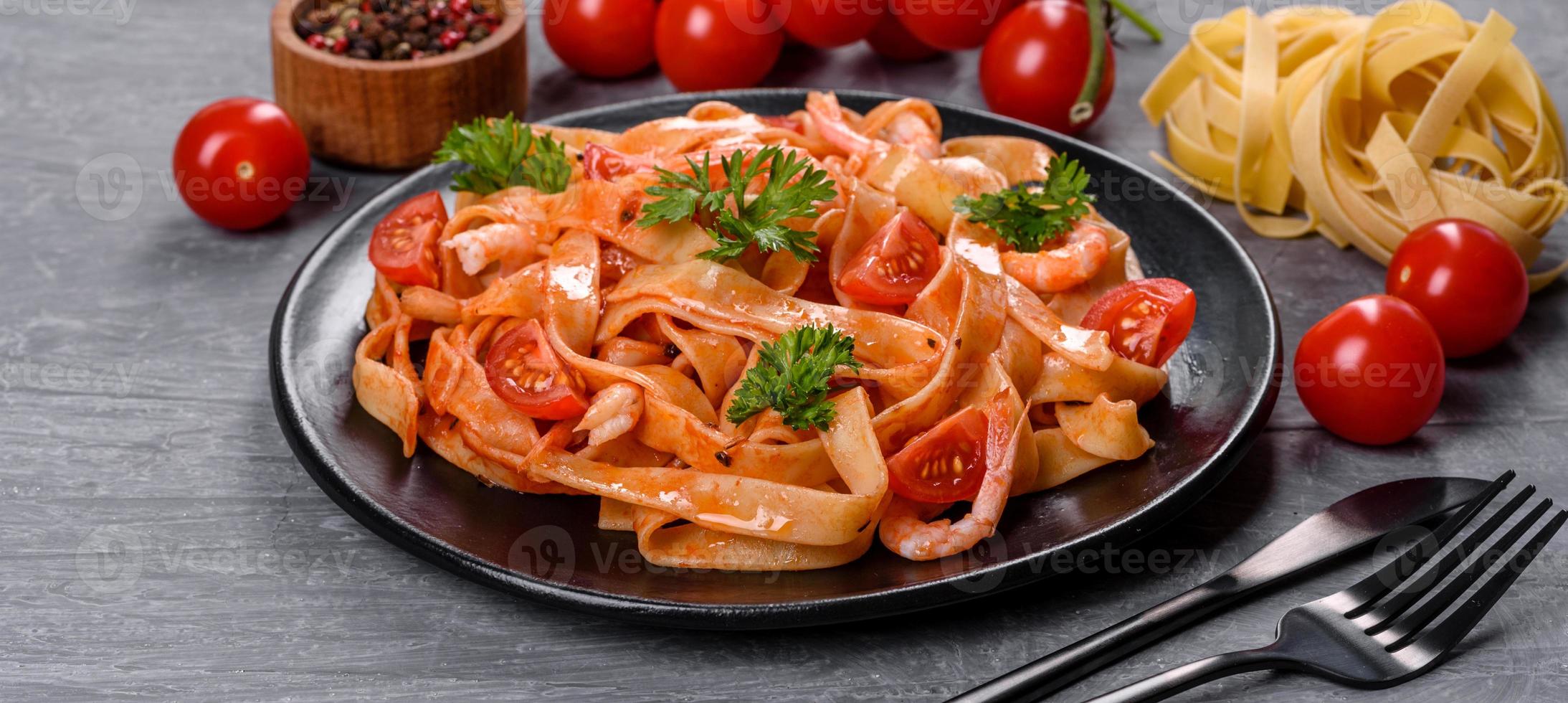 fettuccine con gamberi, pomodorini, salsa, spezie ed erbe aromatiche foto